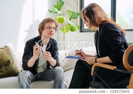 Teenage boy in mental therapy session, talking with behavioral psychologist Teenage boy in mental therapy session, talking with behavioral psychologist 128572041