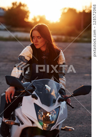 Amazing sunlight. Woman is with motorcycle outdoors Amazing sunlight. Woman is with motorcycle outdoors 128572068
