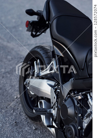 Black colored vehicle. Close up view of modern motorcycle that is parked outdoors Black colored vehicle. Close up view of modern motorcycle that is parked outdoors 128572074