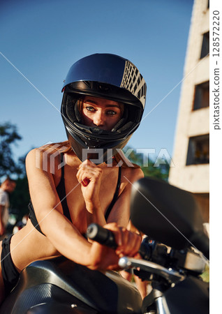 In protective helmet. Hot woman in underwear is with motorcycle outdoors In protective helmet. Hot woman in underwear is with motorcycle outdoors 128572220