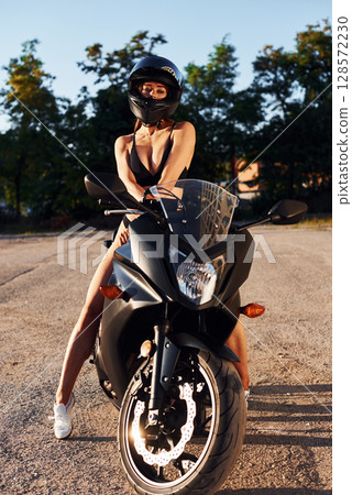 In protective helmet. Hot woman in underwear is with motorcycle outdoors In protective helmet. Hot woman in underwear is with motorcycle outdoors 128572230
