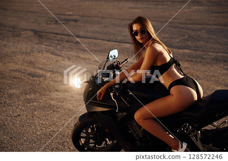 Side view, sitting. Hot woman in underwear is with motorcycle outdoors Side view, sitting. Hot woman in underwear is with motorcycle outdoors 128572246