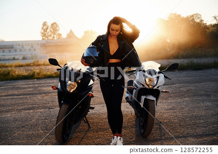Between two vehicles, against smoke. Woman is with motorcycle outdoors 128572255