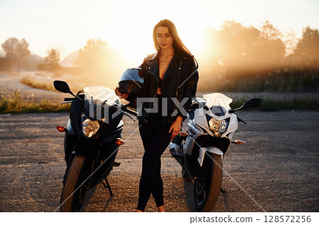 Between two vehicles, against smoke. Woman is with motorcycle outdoors 128572256