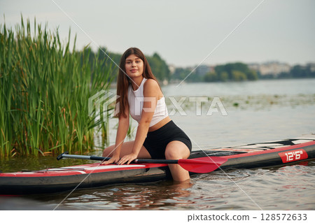 Sitting, relaxing, enjoying the nature. Young woman is on sup boards in the lake 128572633
