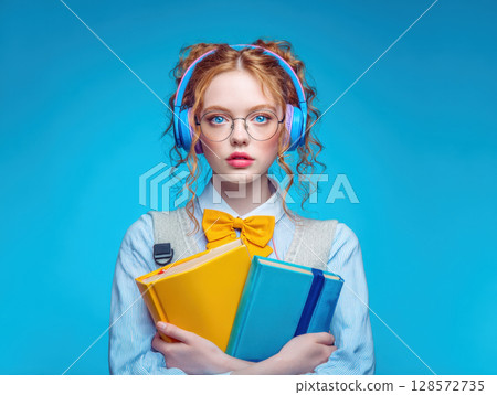 A striking portrait of a young person with vibrant red hair, wearing blue headphones and holding a stack of colorful books, exuding a sense of readiness for learning and self-expression 128572735