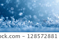 A close-up of delicate snowflakes glistening on a frosty surface, bathed in soft blue light and surrounded by bokeh, creating a serene and enchanting winter wonderland backdrop 128572881