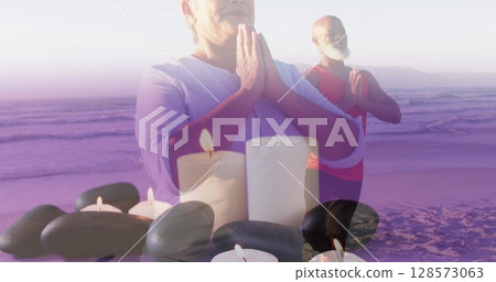 Image of senior african american couple practicing yoga at beach over candles 128573063