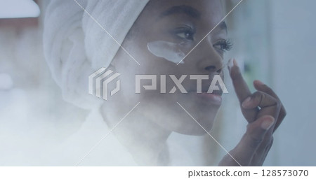 Image of african american woman using cream on face over light spots Image of african american woman using cream on face over light spots 128573070