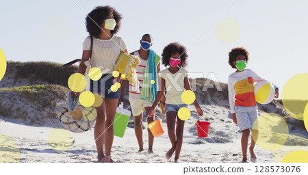 Image of african american family with face masks walking at beach over light spots 128573076