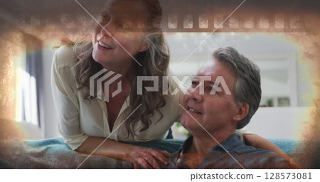Image of happy senior caucasian couple watching tv over frame 128573081