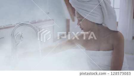 Image of african american woman preparing bath over bathroom 128573083