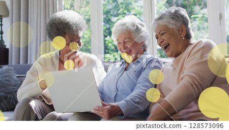 Image of happy senior diverse female friends using laptop over light spots Image of happy senior diverse female friends using laptop over light spots 128573096
