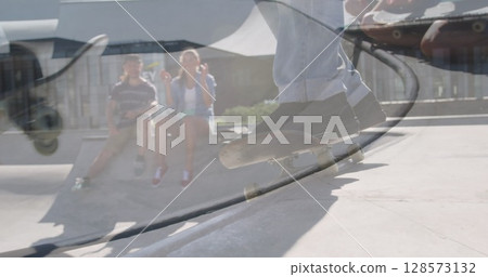 Image of caucasian man skateboarding with caucasian couple sitting in skate park 128573132