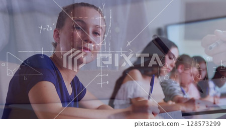 Image of mathematical equations over school children writing in classroom 128573299