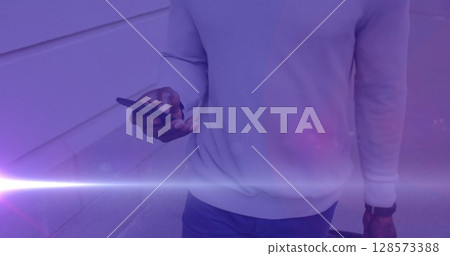 Image of coloured lights over african american man walking to work, using smartphone in street 128573388