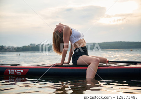 Sitting and relaxing. Young woman is on sup boards in the lake Sitting and relaxing. Young woman is on sup boards in the lake 128573485