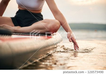 Touching the water, close up view. Young woman is on sup boards in the lake 128573490