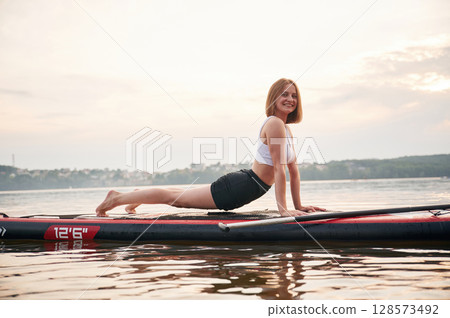 Exercises for the spine. Young woman is on sup boards in the lake Exercises for the spine. Young woman is on sup boards in the lake 128573492