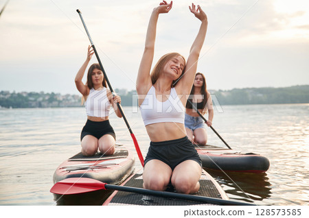Front view. Young women are on sup boards in the lake 128573585