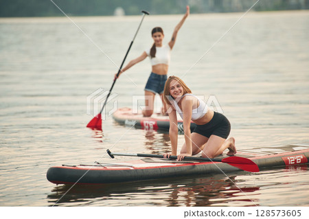 Young women are on sup boards in the lake 128573605