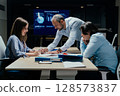 Senior executive mentoring junior colleague in modern office with presentation screen 128573837