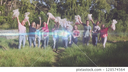 Image of lights over cheering diverse volunteer group picking up rubbish in countryside 128574564