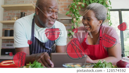 Multiple burger icons against african american senior couple using digital tablet in the kitchen Multiple burger icons against african american senior couple using digital tablet in the kitchen 128574592