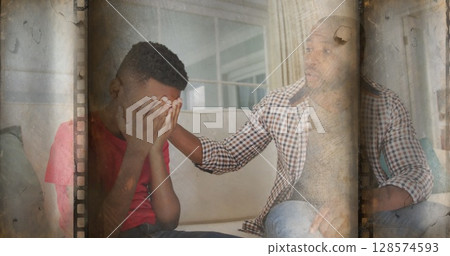 Old film overlay effect against african american father consoling his stressed son 128574593