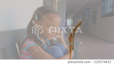 Composite image of wooden figurine against stressed african american girl in corridor at school Composite image of wooden figurine against stressed african american girl in corridor at school 128574615