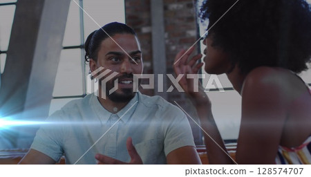 Blue light trails against african american male and female office colleagues discussing at office 128574707