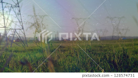 Composite image of white spots against time-lapse of green and electric towers against blue sky Composite image of white spots against time-lapse of green and electric towers against blue sky 128574731