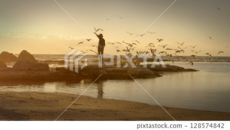 Image of silhouette of man and birds flying over sea in background Image of silhouette of man and birds flying over sea in background 128574842