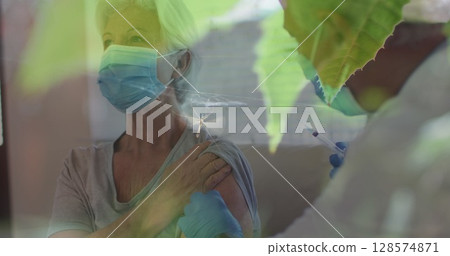 Mosquito stuck in a spider web against male doctor giving an injection to senior caucasian woman Mosquito stuck in a spider web against male doctor giving an injection to senior caucasian woman 128574871