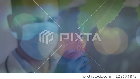 Image of gloving lights over caucasian male doctor with syringe 128574872