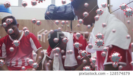 Image of virus cells floating over diverse group of male football players in changing room 128574879