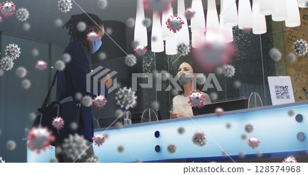 Image of covid 19 cells over diverse man and woman wearing face masks in hotel reception 128574968