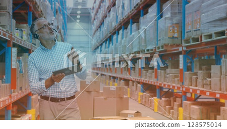 Image of biracial male worker with tablet talking in warehouse 128575014