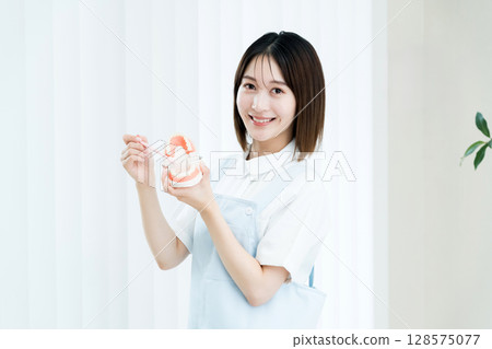 拿著牙刷和牙齒模型的牙科工作人員女士 128575077