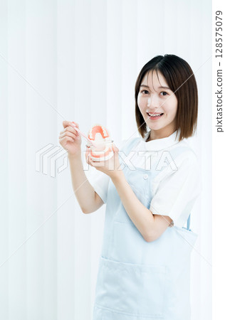 Dental staff woman holding a toothbrush and a tooth model Dental staff woman holding a toothbrush and a tooth model 128575079
