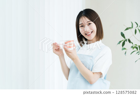 拿著牙刷和牙齒模型的牙科工作人員女士 拿著牙刷和牙齒模型的牙科工作人員女士 128575082