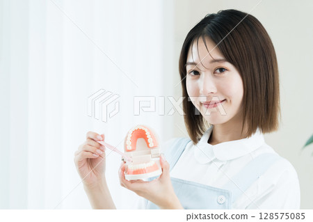 拿著牙刷和牙齒模型的牙科工作人員女士 128575085