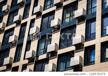 Facade of skyscraper with air conditions and windows. Exterior of high rise building. Modern architecture. Business office building. Geometric lines in architecture. Geometric lines in architecture 128576375