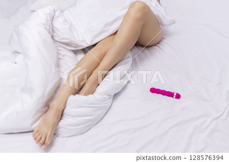 Young woman holding sex toy dildo vibrator in bed 128576394
