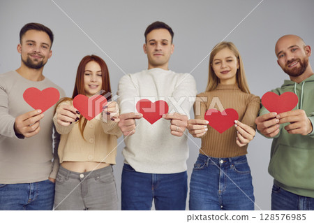 Group of young people holding paper red love heart, showing loving relationships, understanding 128576985