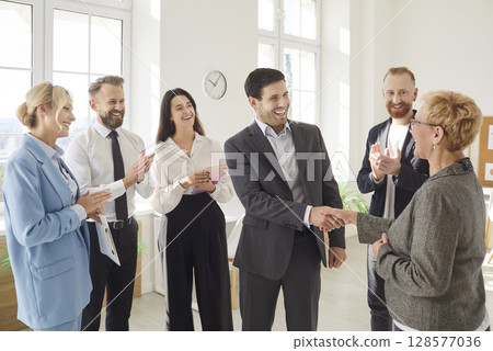 Business people in office making deal shaking hands with each other celebrating success. Business people in office making deal shaking hands with each other celebrating success. 128577036