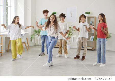 Happy preteen friends applauding their classmate dancing, enjoying fun group activity together. 128577038