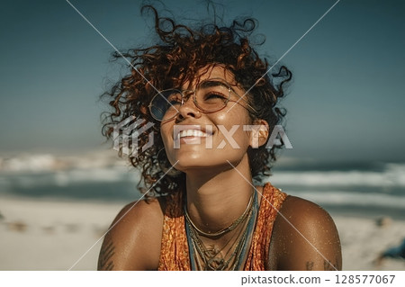 Happy tourist enjoying sunlight on beach with curly hair and trendy glasses 128577067