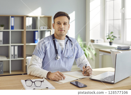 Smiling Doctor At Desk in Hospital Office Smiling Doctor At Desk in Hospital Office 128577106