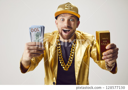 Surprised Rich Man In Golden Suit Holding Stack Of Cash And Gold Bar Surprised Rich Man In Golden Suit Holding Stack Of Cash And Gold Bar 128577130